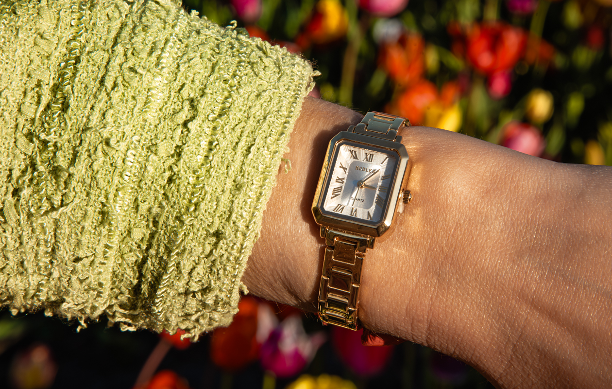 Hodler dameshorloge met gouden kast en bloemen op de achtergrond